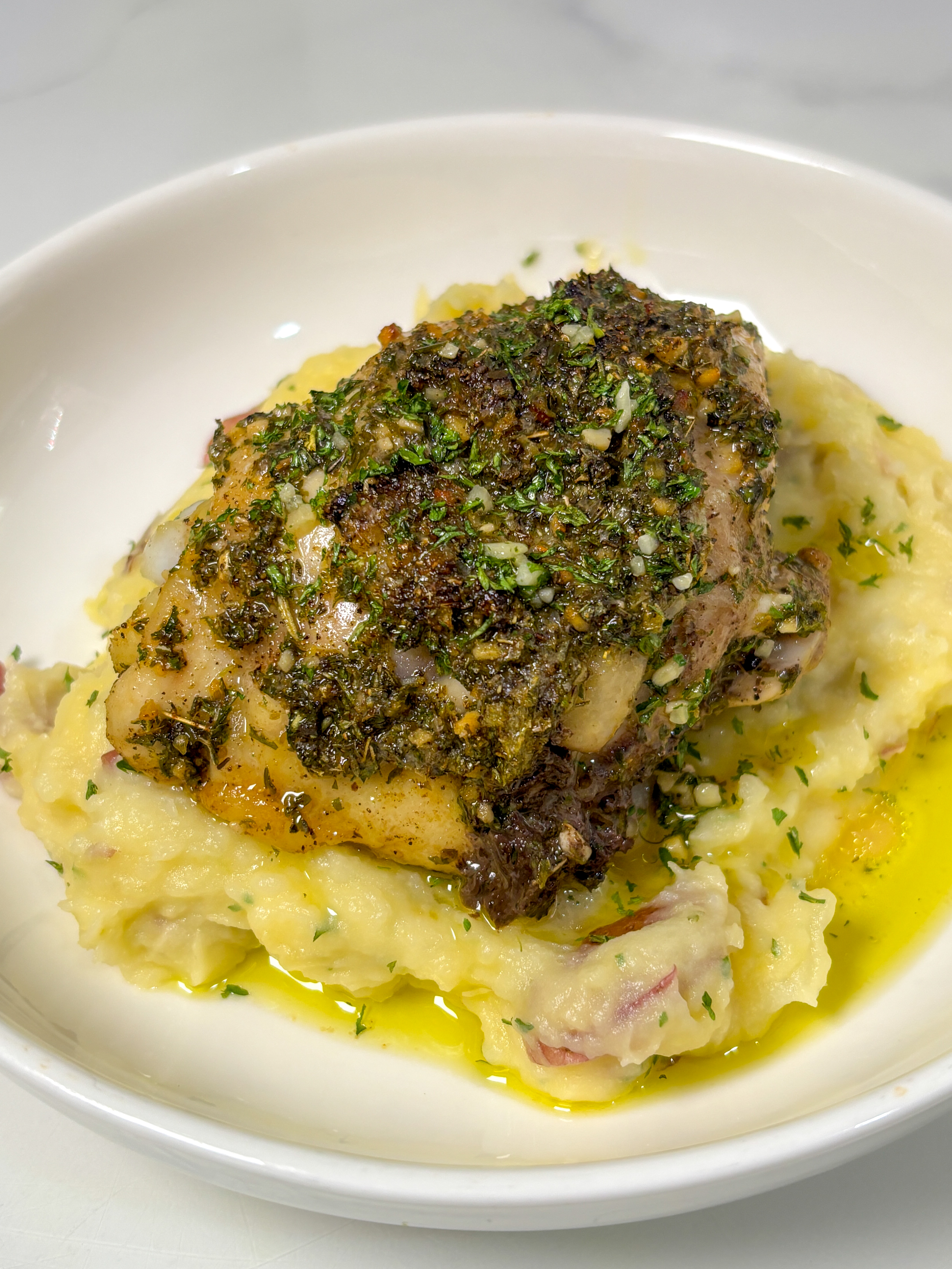 lemon and herb oven baked chicken thighs on top of mashed potatoes